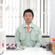 Shinya Arino sits at a desk next to a Nintendo Famicom and in front of a small TV.